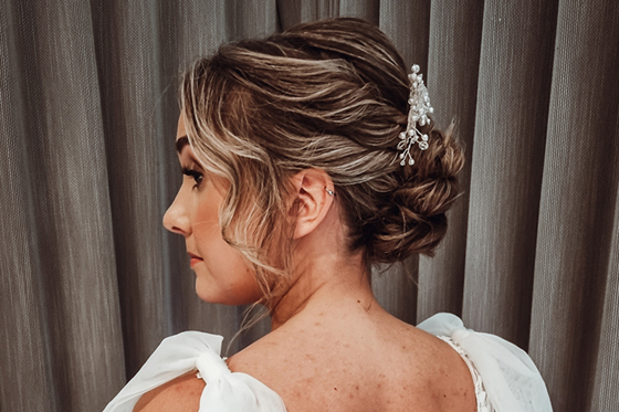 View of brides wavy updo with accessory from back